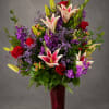 Tall bouquet of red roses and pink lilies in a red vase
