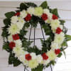 Red and white floral wreath on a black stand