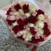 Bouquet of red, white, and pink roses wrapped in pale pink paper
