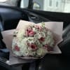 Bouquet of pink and white roses wrapped in pale pink paper