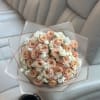 Bouquet of peach roses with white filler flowers wrapped in translucent paper
