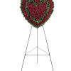 Heart-shaped floral wreath of red roses and carnations on a stand