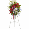 Standing floral spray with red carnations, white lilies, and blue flowers on an easel