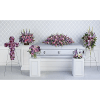 Pink and purple funeral flowers arranged around a silver casket