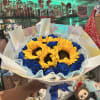 Bouquet of yellow sunflowers and blue roses wrapped in white paper
