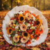 Bouquet of orange, cream, and white flowers wrapped in white paper