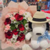 Bouquet of red roses and pink carnations with a plush dog wearing a hat