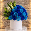Blue roses and white lilies arranged in a white hat box