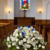 White floral arrangement with blue accents in a church aisle