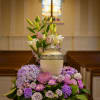 Purple and white floral arrangement with lilies in a decorative urn