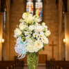 White floral arrangement in a clear glass vase with a ribbon bow