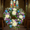 Heart-shaped floral wreath on a stand with white, purple, and blue flowers