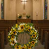 Sunflower and white daisy wreath on a stand inside a church
