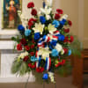 Standing floral spray with red, white, and blue flowers on an easel