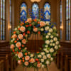 Large floral wreath on a stand in a church aisle
