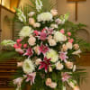 Large pink and white funeral spray with lilies and roses in a church