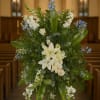 Large floral standing spray with white lilies and blue accents