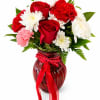 Red roses and white chrysanthemums in a red glass vase with a ribbon