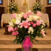 Pink and white floral arrangement in a glass vase with a pink ribbon