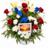 Basket arrangement of red, white, yellow, and blue flowers with a sunset photo