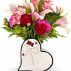 Pink lilies and red carnations in a heart-shaped vase with pearl bow detail.