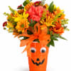 Orange Halloween bucket filled with mixed flowers and a ribbon bow