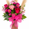Pink and red mixed bouquet in a frosted vase with a bright ribbon