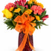 Bright mixed bouquet in a red vase with an orange ribbon