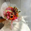 Hand-tied bouquet of pink roses, lilies, and orange flowers wrapped in white paper