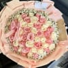 A lush, round bouquet of tightly packed pink and cream roses edged