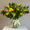 Bouquet of yellow and purple tulips in a glass vase with a ribbon