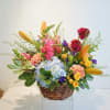 Mixed bouquet in a wicker basket with lilies, hydrangea, roses, and carnations