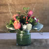 Pink roses in a green glass jar with berries and foliage