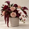 Bouquet of burgundy and blush roses with white orchids in a beige vase
