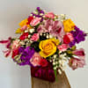 Mixed bouquet with yellow roses, pink and purple flowers in a magenta vase