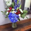 A bold cluster of blue hydrangea meets classic red roses and white