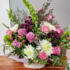 Basket arrangement of pink roses, white daisies, and purple flowers