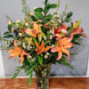Orange lilies arranged in a clear vase with white filler flowers