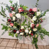 A lush grapevine wreath arranged on a black metal easel, this large