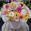 Pink, white, and yellow flowers arranged in a round box
