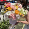 Large pastel bouquet in a white hatbox held by a woman outdoors