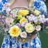Basket of yellow and blush roses with pastel filler flowers