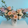 Peach and cream roses in a white vase with lavender filler flowers
