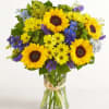 Bouquet of yellow sunflowers and mixed blue-purple flowers in a glass vase