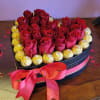 Heart-shaped box of red roses with gold-wrapped chocolates and a pink ribbon