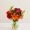 Colorful bouquet of lilies, roses, and carnations in a clear glass vase