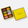 Box of colorful macarons with a yellow lid beside it