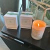 Two boxed gifts and a lit candle on a dark table