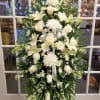Large white funeral spray with lilies, roses, and chrysanthemums on an easel