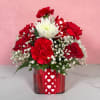 Red and white flower arrangement in a glass vase with heart ribbon